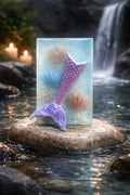 Mermaid tail soap on a rock with a waterfall and candles in the background