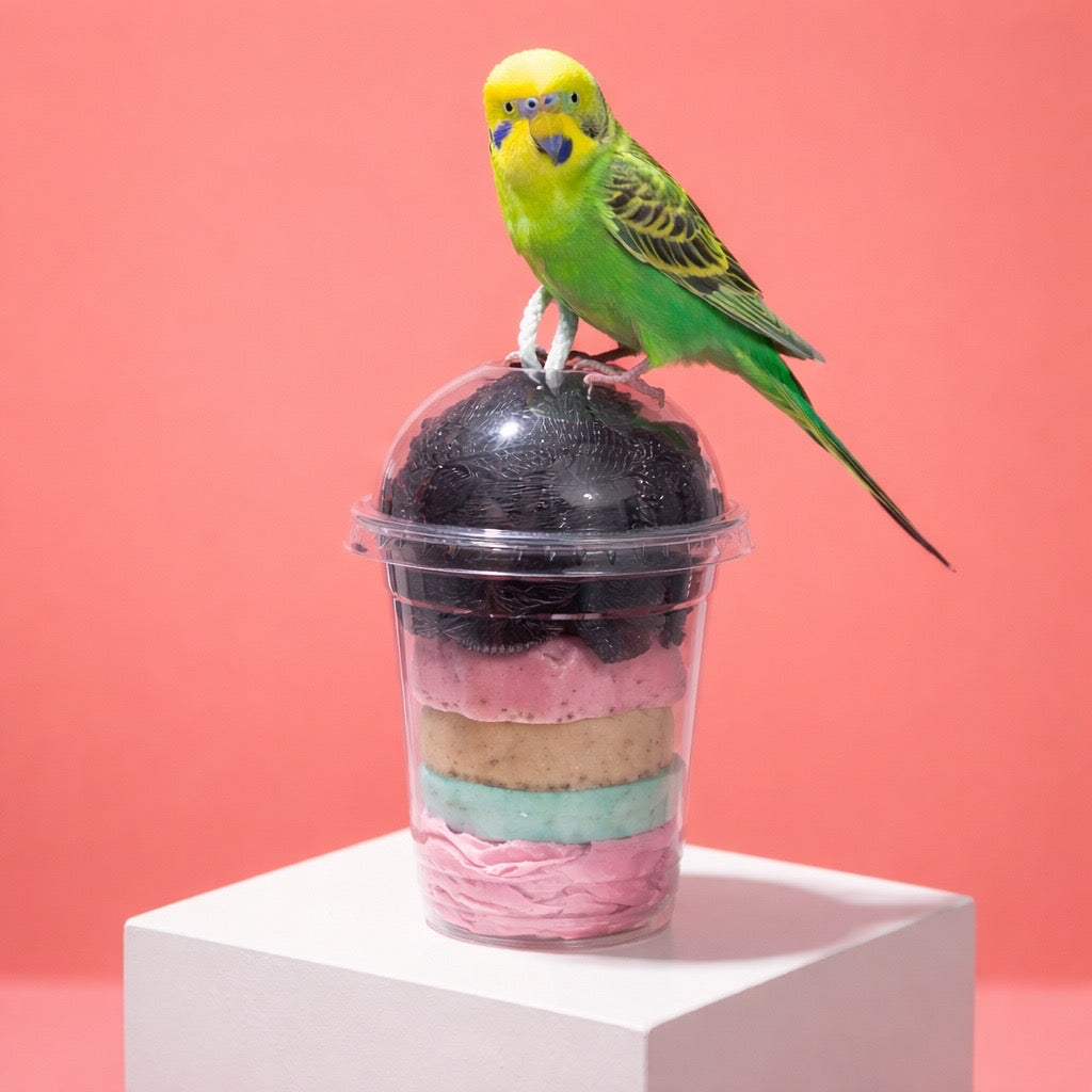 Green parakeet perched on a layered soap ice cream dessert against a pink background