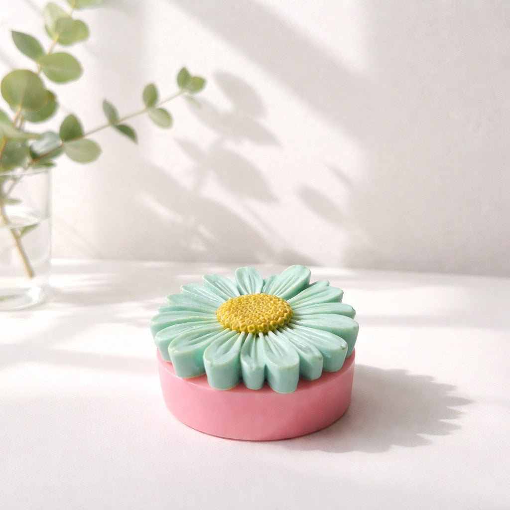 Decorative soap with a daisy design on a pink surface 