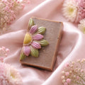 Handmade soap bar with floral design on a soft pink fabric background