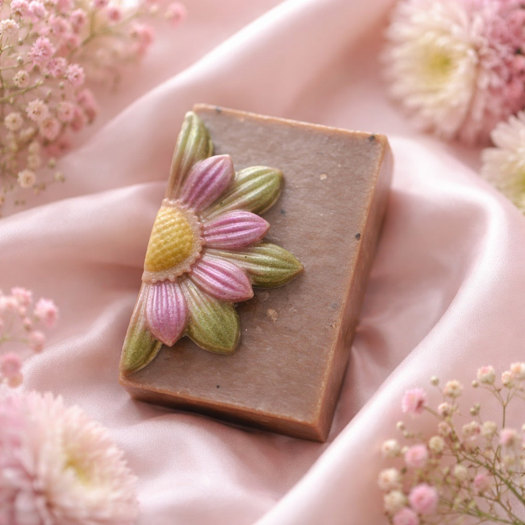 Handmade soap bar with floral design on a soft pink fabric background